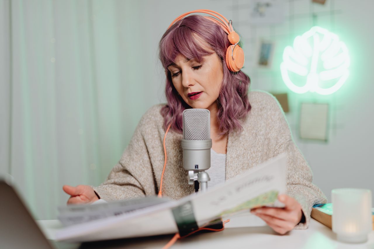 Mastering the First Impression: Your intriguing post title goes here Woman with headphones podcasting indoors, speaking into a microphone while reading a book.